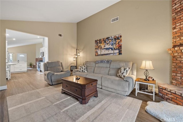 living room featuring high vaulted ceiling, visible vents, and wood finished floors