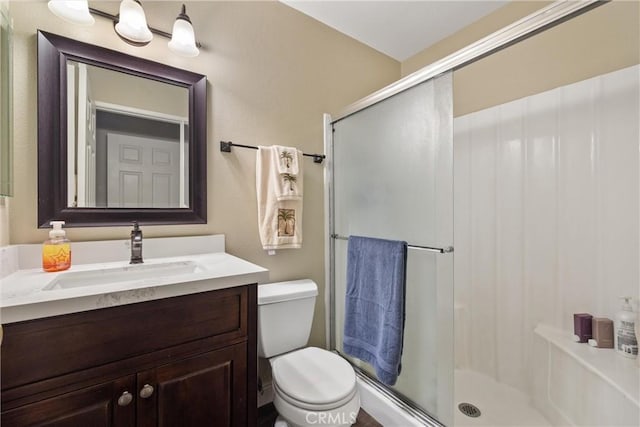 bathroom featuring toilet, a shower stall, and vanity