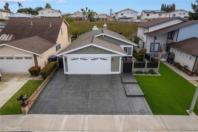 view of front of home with a garage, fence, driveway, a residential view, and a front lawn