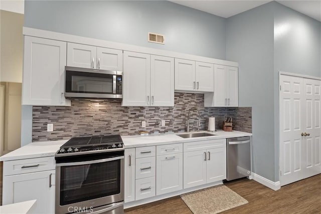 kitchen with a sink, visible vents, white cabinetry, appliances with stainless steel finishes, and backsplash