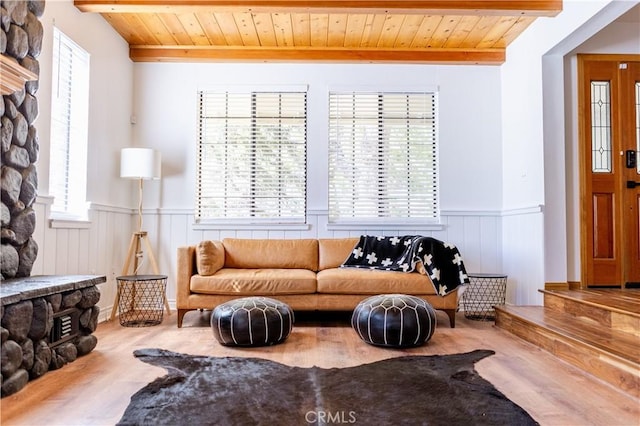 living area featuring wooden ceiling, beamed ceiling, and a wainscoted wall