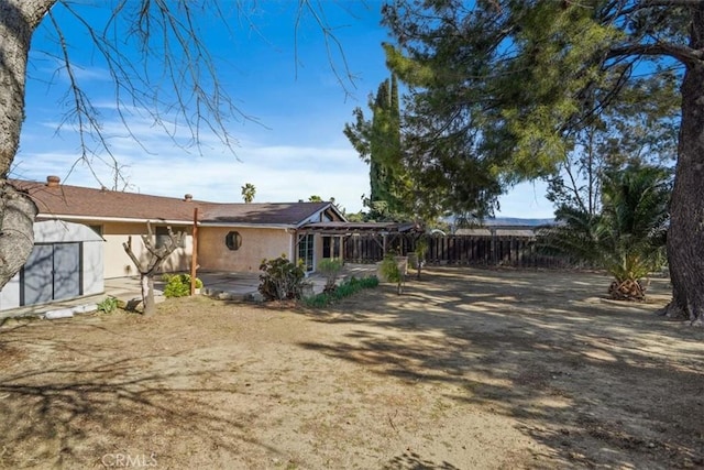 rear view of house featuring a patio, fence, and stucco siding