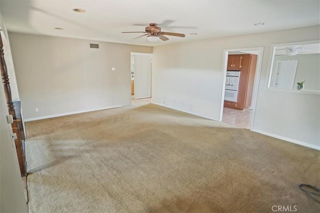 empty room featuring light carpet, ceiling fan, visible vents, and baseboards