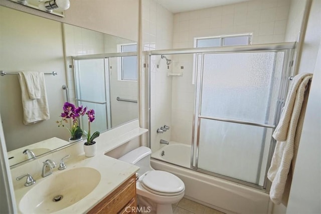 full bath featuring shower / bath combination with glass door, tile patterned flooring, vanity, and toilet