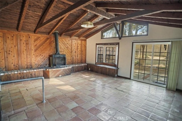 interior space featuring vaulted ceiling with beams, wooden ceiling, a wood stove, and wooden walls