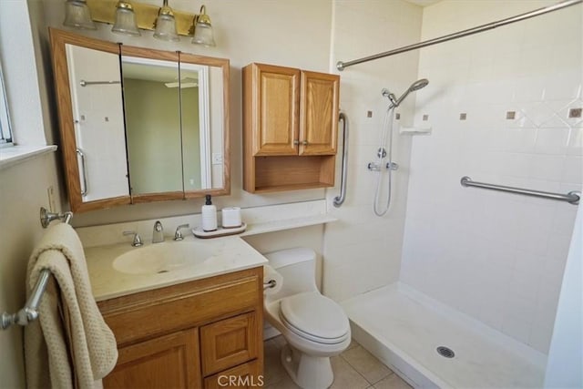 bathroom with vanity, tile patterned flooring, a tile shower, and toilet