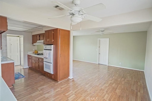 kitchen with visible vents, light countertops, light wood-type flooring, white appliances, and under cabinet range hood