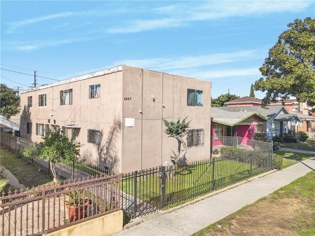 view of side of property featuring a yard, a fenced front yard, and stucco siding