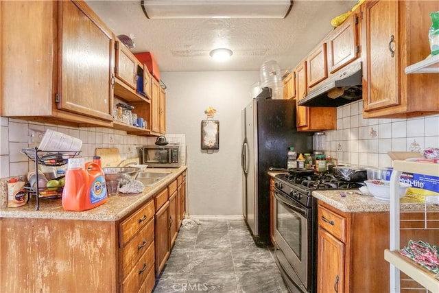 kitchen with light countertops, stainless steel microwave, a textured ceiling, gas range, and under cabinet range hood