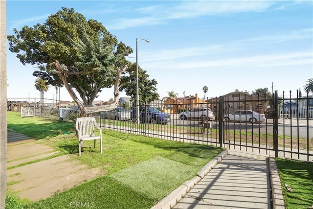 surrounding community with a residential view, a gate, fence, and a lawn