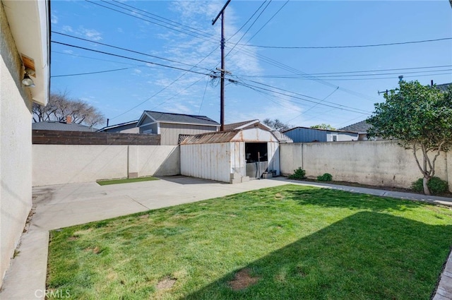 view of yard featuring an outbuilding, a patio area, a fenced backyard, and a storage shed