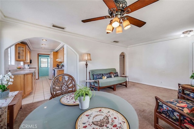 dining space featuring visible vents, arched walkways, a ceiling fan, light colored carpet, and ornamental molding