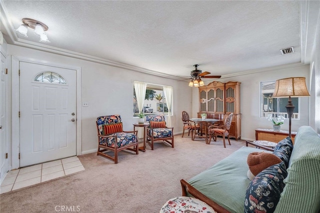 carpeted living room with ceiling fan, visible vents, a textured ceiling, and ornamental molding