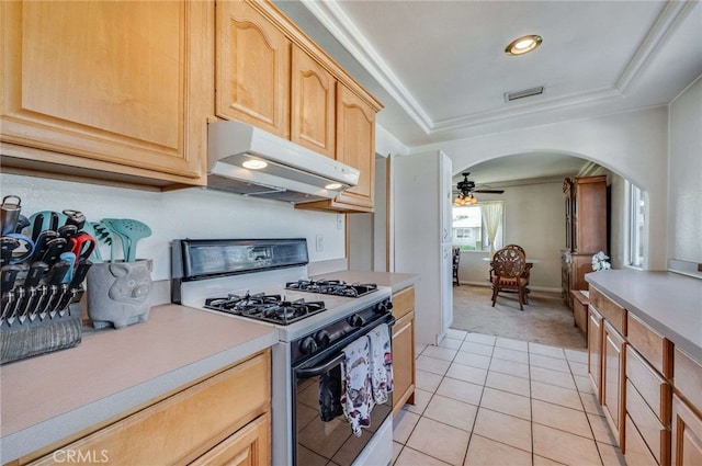 kitchen featuring under cabinet range hood, arched walkways, light countertops, and gas stove