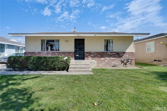 view of front of home featuring brick siding, stucco siding, and a front yard