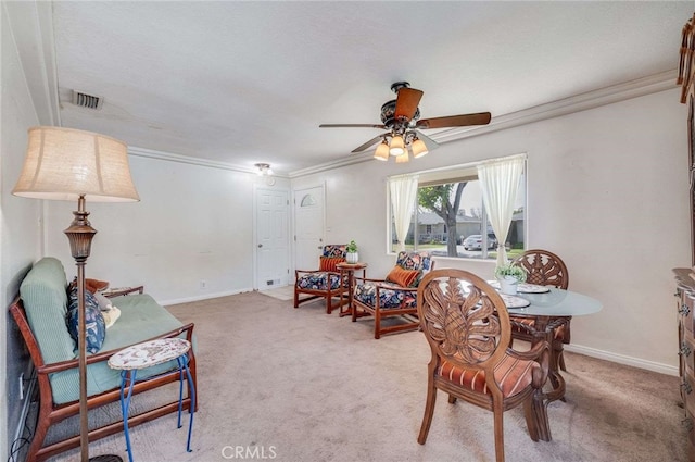 carpeted dining area with baseboards, visible vents, ceiling fan, and crown molding