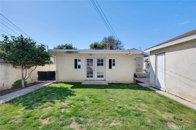 back of house featuring stucco siding, fence, a lawn, and french doors