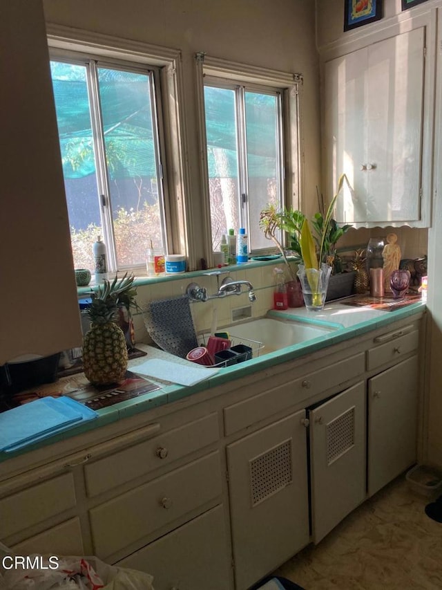 kitchen with white cabinetry, a sink, and tile countertops