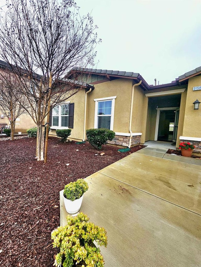 view of side of home with stone siding and stucco siding