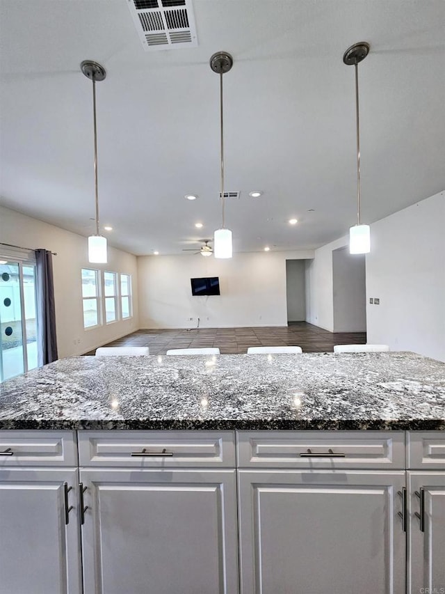 kitchen with visible vents, dark stone countertops, and white cabinetry