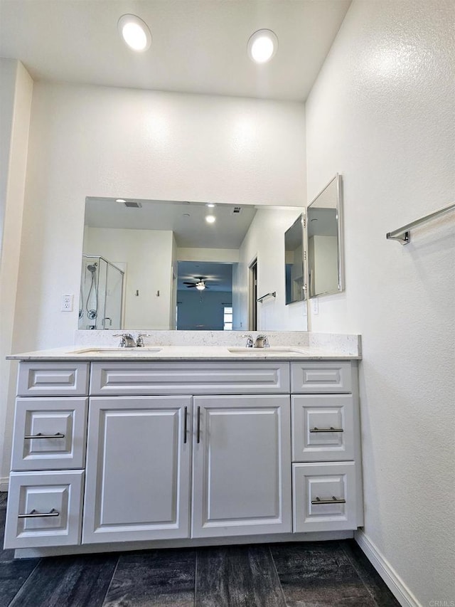 full bath featuring double vanity, an enclosed shower, baseboards, and a sink