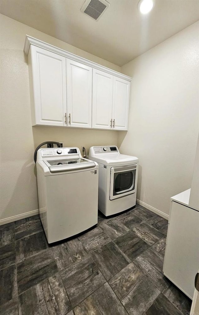 clothes washing area featuring washer and dryer, cabinet space, visible vents, and baseboards