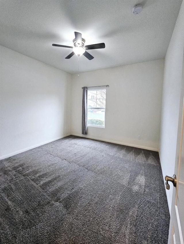 carpeted spare room with baseboards, a ceiling fan, and a textured ceiling