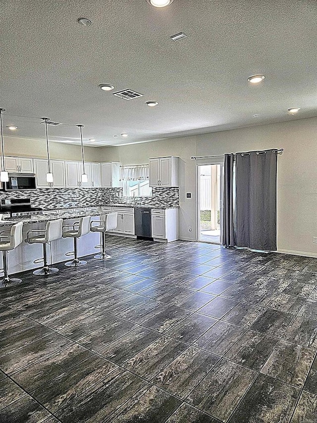 kitchen with visible vents, a breakfast bar, white cabinets, appliances with stainless steel finishes, and backsplash
