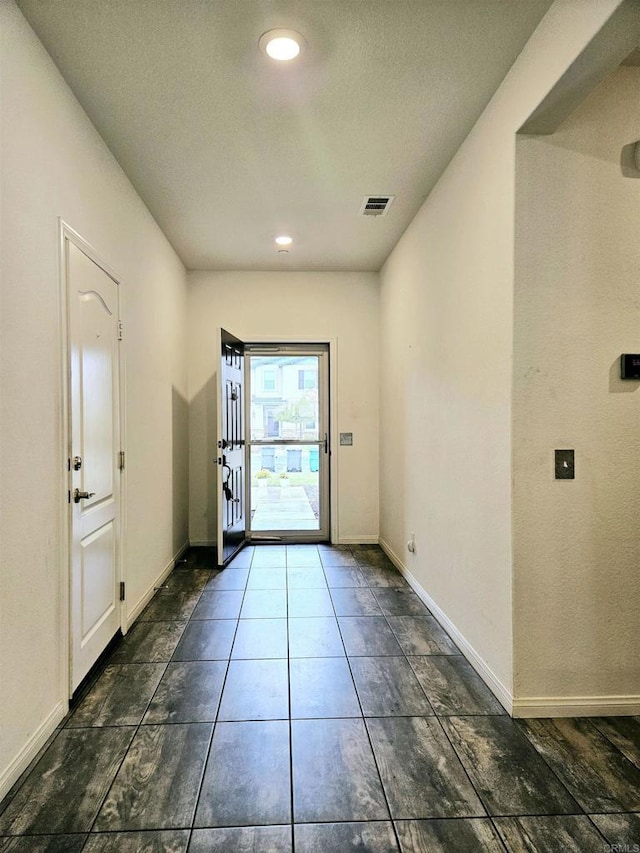 entryway with baseboards, dark tile patterned floors, recessed lighting, and visible vents