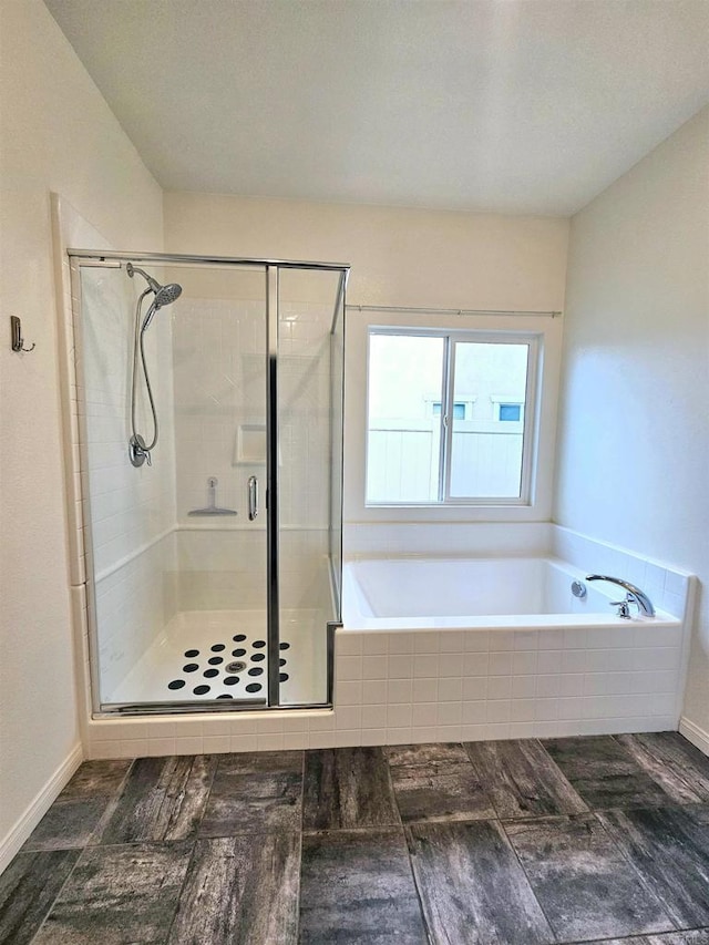 bathroom featuring baseboards, a garden tub, and a stall shower