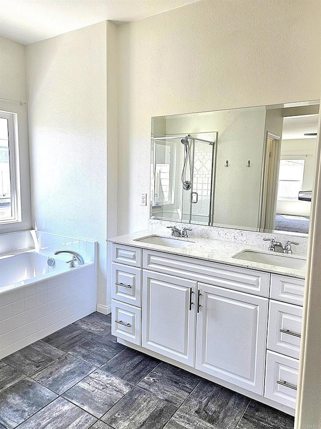 full bath with double vanity, a sink, a garden tub, and a stall shower