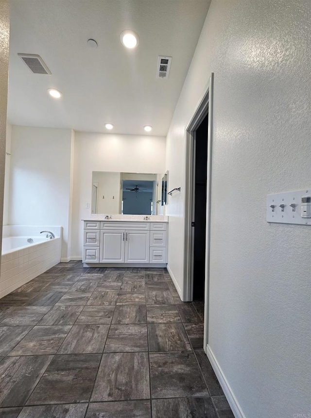 bathroom with double vanity, baseboards, a bath, and visible vents