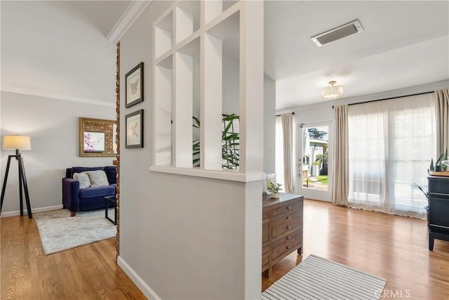 entryway with visible vents, crown molding, baseboards, and wood finished floors