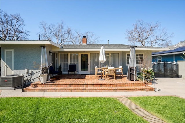 back of property featuring stucco siding, cooling unit, a chimney, a patio, and a gate