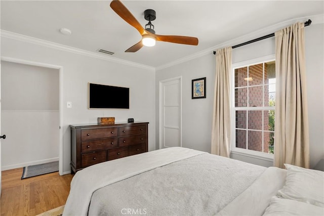 bedroom with visible vents, wood finished floors, crown molding, baseboards, and ceiling fan