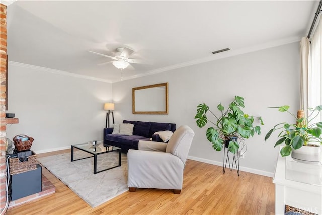 living area with light wood-type flooring, baseboards, and ornamental molding