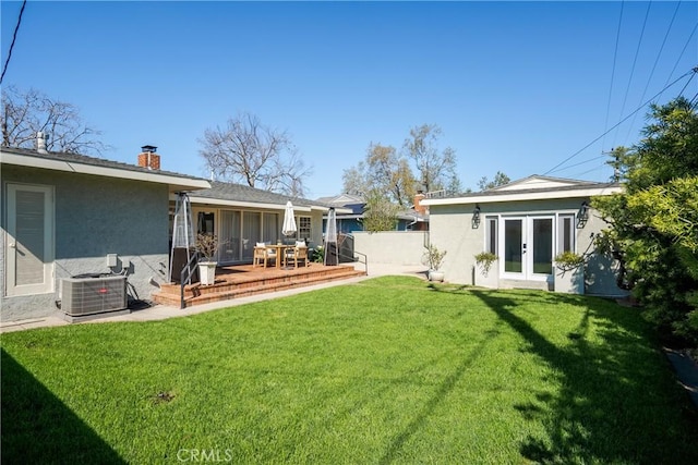 view of yard with cooling unit, french doors, and fence