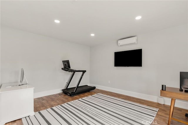 exercise area featuring recessed lighting, a wall unit AC, and wood finished floors