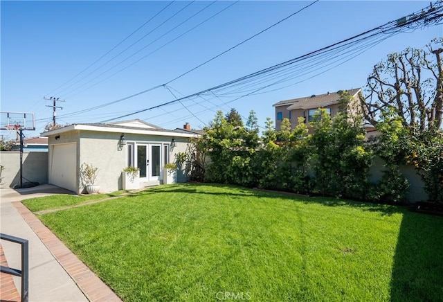 view of yard with an outbuilding, a garage, french doors, and fence