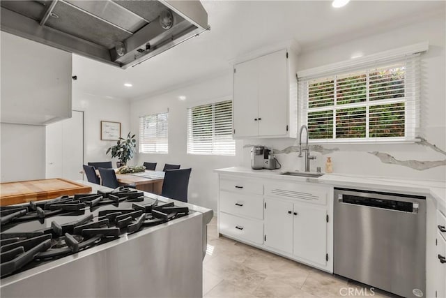 kitchen with a sink, wall chimney range hood, white cabinets, light countertops, and dishwasher