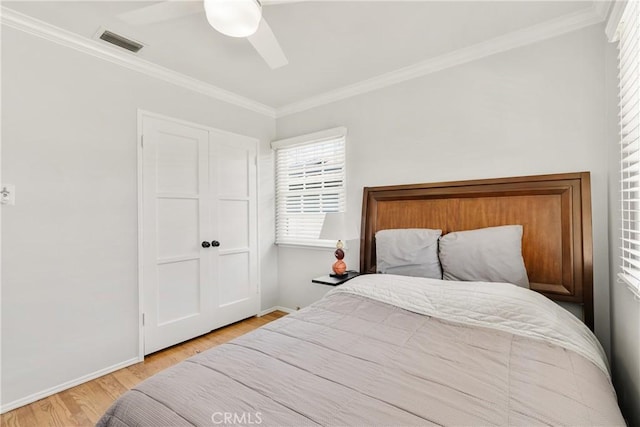 bedroom featuring crown molding, wood finished floors, visible vents, and baseboards