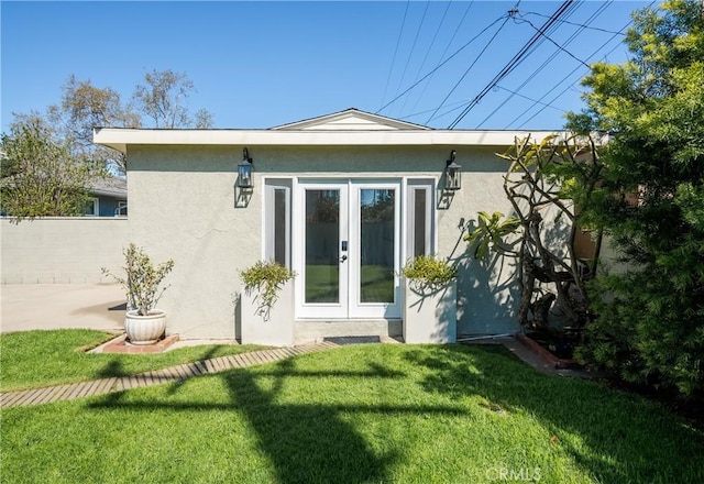 rear view of house featuring fence, stucco siding, french doors, a yard, and a patio