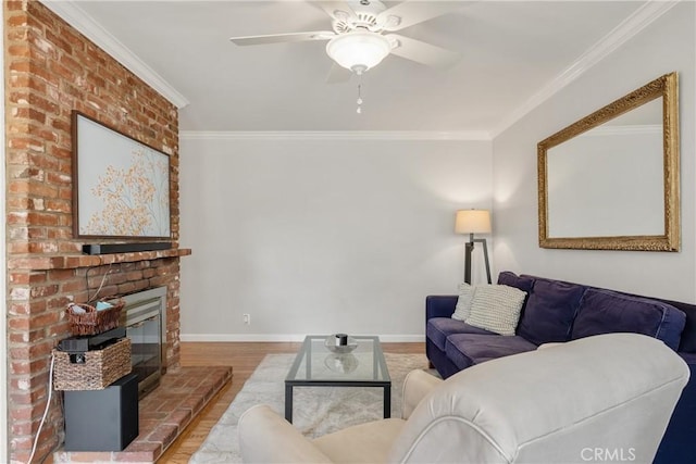 living area featuring baseboards, wood finished floors, ornamental molding, and a fireplace