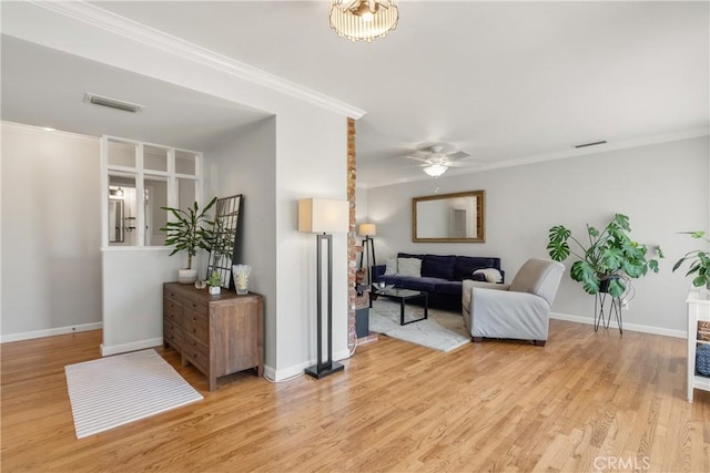 living room with visible vents, ornamental molding, and light wood-style flooring