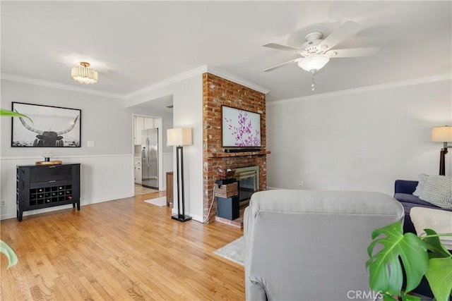 living area with crown molding, a fireplace, and light wood-type flooring