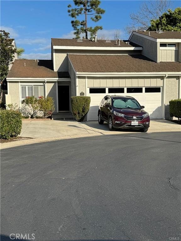 view of property featuring a garage, concrete driveway, and stucco siding