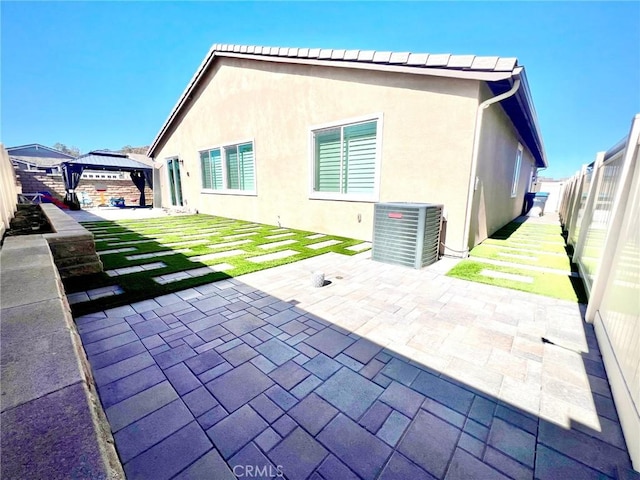 back of house with a patio, a fenced backyard, a gazebo, central AC, and stucco siding