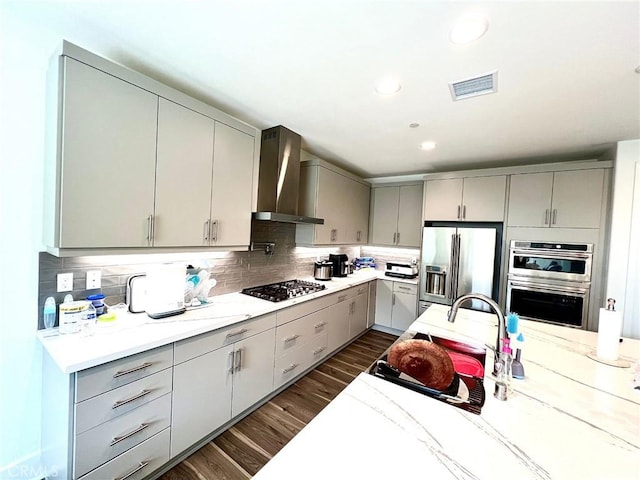 kitchen featuring appliances with stainless steel finishes, wall chimney exhaust hood, and gray cabinetry