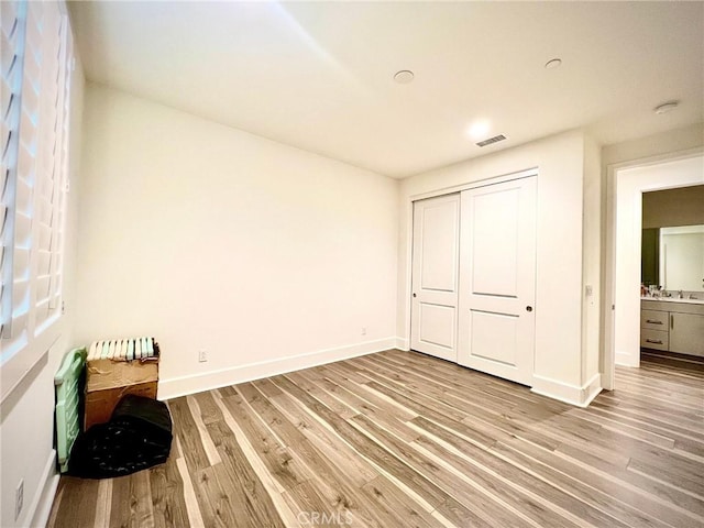 bedroom featuring light wood-style floors, a closet, visible vents, and baseboards