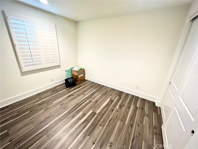 spare room with baseboards and wood finished floors